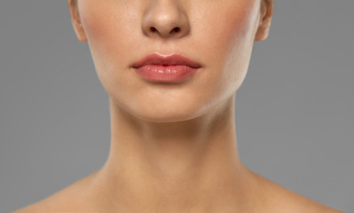 beauty, makeup and people concept - close up of beautiful young woman face and neck over grey backgr