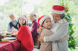 © linghaa - Big Asian family celebration in Christmas day, grandmother hug and looking at granddaughter in front of meal table of family which smiling and felling happy at home. Merry Xmas and happy new year.