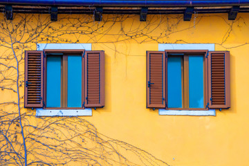 Yellow facade of a house with windows with brown shutters. Croatia