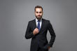 Handsome young bearded business man in classic black suit shirt tie posing isolated on grey background studio portrait. Achievement career wealth business concept. Mock up copy space. Looking camera.