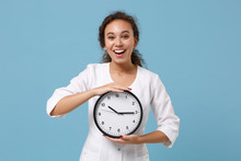Cheerful African American Female Doctor Woman In White Medical Gown Holding Round Clock Isolated On Blue Background Studio Portrait. Healthcare Personnel Medicine Health Concept. Mock Up Copy Space.