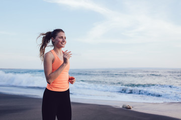 Happy young woman running along beach