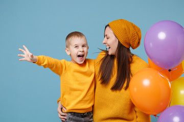 Wall Mural - Woman in yellow clothes have fun with cute child baby boy 4-5 years old celebrating birthday holiday party with colorful air balloons. Mommy son isolated on blue background. Family childhood concept.