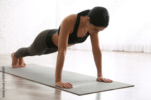 Fotomural Young woman practicing plank asana in yoga studio