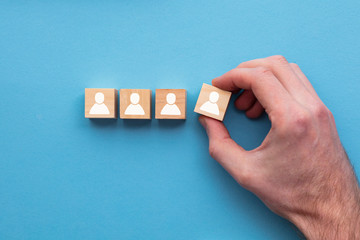 Hand choosing a wooden person block from a set. Employment choice concept