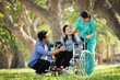 © chayathon2000 - Asian senior woman sitting on the wheelchair with her son  happy smile face on the green park