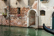 An old brick building in Venice with a flooded porch. A gondola boat floats nearby. The brick wall of the building collapses.