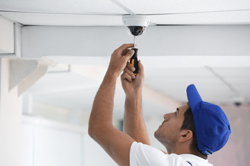 Poster - Technician installing CCTV camera on ceiling indoors