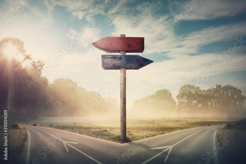 Fotografía Surreal landscape with a split road and signpost arrows showing two different courses, left and right direction to choose