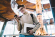 © GalakticDreamer - Young man in glasses carrying laptop with notebook and using smartphone