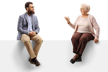 Senior Lady Sitting On A Blank Panel And Talking To A Younger Bearded Man