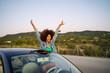 © Westend61 - Young woman during road trip with raised arms