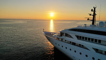 Aerial drone photo of luxury yacht docked in Aegean deep blue sea at sunset with beautiful golden colours, Greece