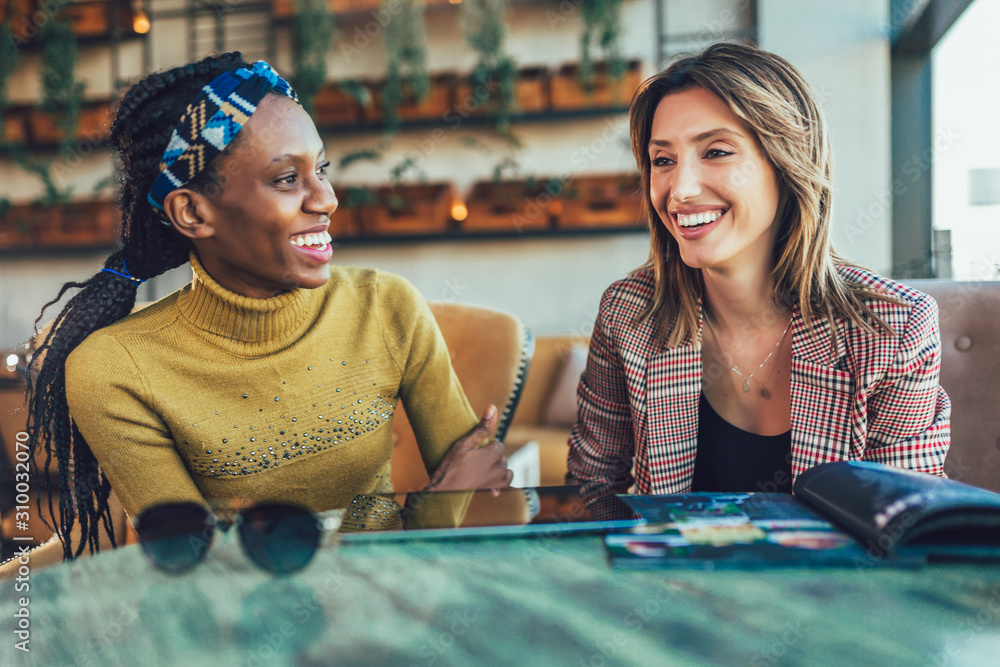 Two female friends talking at a coffee shop - obrazy, fototapety, plakaty 