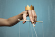 Concept of manipulation. Hand with crown holds strings for manipulation. Image