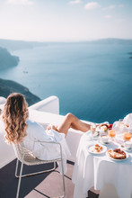 Young Woman With Blonde Hair Having Breakfast In Santorini Greece