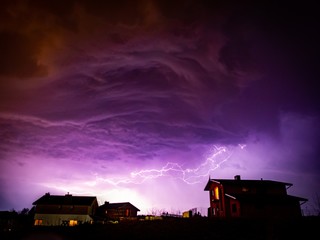 Wall Mural - valley with houses on it under a cloudy sky during storm in the night
