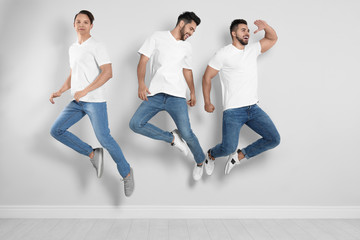 Wall Mural - Group of young men in stylish jeans jumping near light wall