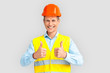 © Viktoriia - Construction. Mature man in hardhat and uniform standing isolated on white showing thumbs up laughing playful