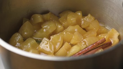 Wall Mural - Opening paper cover to see cooked apple with cinnamon inside a metal pot.