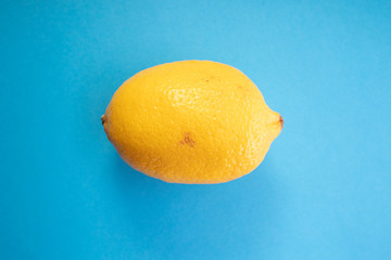 One ripe yellow lemon on colour background. Healthy vegetarian citrus food..