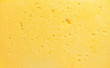 Cheese texture. Background of fresh yellow cheese with holes
