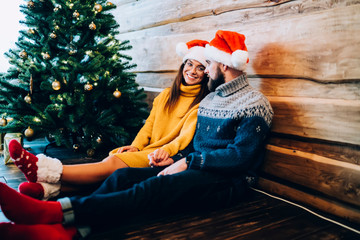 Wall Mural - Smiling young lovers holding hands near Christmas tree