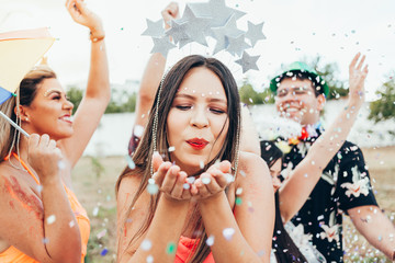 Wall Mural - Brazilian Carnival. Young woman in costume enjoying the carnival party blowing confetti