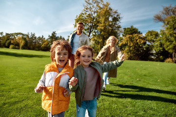 Sunny weekend. Excited family running outdoors on a sunny day