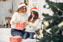 Beautiful Mother In A White Sweater. Family With Cristmas Gifts. Little Girl In A Santas Hat