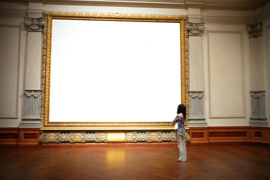 woman with folded arms standing in front of and looking at big blank painting canvas with huge frame