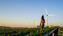 One Woman Stands In The Middle Of A Wide Field Have Large Wind Turbines, Which Is An Industry That Produces Electricity From Clean Energy.