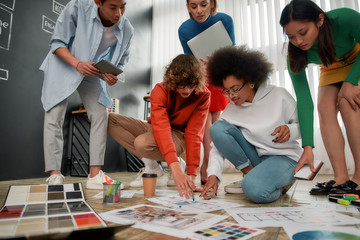 Wall Mural - working on a new project. group of young interior designers in casual clothes discussing sketches, c