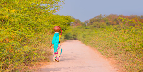 An indian woman in traditional dress carrying water