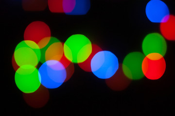 Abstract unfocused background - colorful bokeh of different bubbles on a black background. Modern blurred pattern for design and for Christmas, New year and funny holiday backdrops..