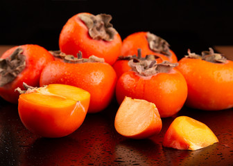 Poster - Ripe persimmons. Fresh persimmon fruits on a dark background. A lot of fruits of fresh persimmon close-up.