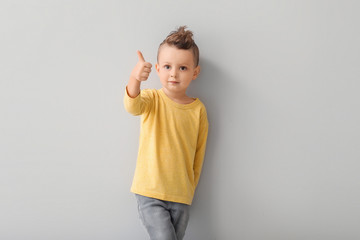 Poster - Portrait of cute little boy showing thumb-up on light background