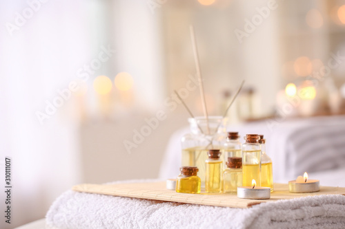 Fotografía Essential oil with glowing candles and reed diffuser on table in spa salon