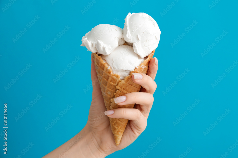 Female hand with sweet ice-cream on color background