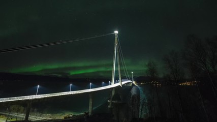 northern lights, polar light or aurora borealis dancing night sky busy bridge in northern norway nar