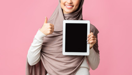 Wall Mural - Muslim girl in headscarf demonstrating digital tablet with black screen