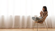 © Prostock-studio - Time to relax. Girl drinking coffee, sitting in wicker chair