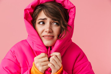 Portrait of young displeased woman in warm hood is freezing