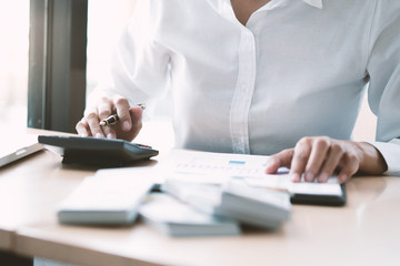 Businesswoman analyzing investment charts and pressing calculator buttons over documents. Accounting Concept.