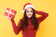 © burdun - Happy woman with red present standing isolated in the santa's hat
