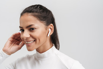 Poster - Image of young brunette woman in sportswear putting on earpods isolated over gray background