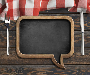 Wall Mural - menu blackboard frame on old wooden dinning table with red tablecloth, tableknife and fork