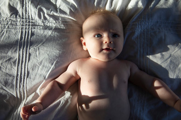 A three month old baby boy laying on a soft blanket with dramatic evening sun