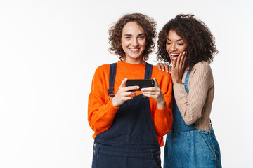 Canvas Print - Multiracial girls friends in denim jumpsuits using mobile phone.