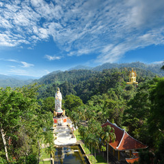 Wall Mural - panorama view to Wat Bang Riang temple in the jungle of Phang Nga province Thailand, with giant seated golden Buddha and large statue of Kwam Im (Guan Yin), the Chinese Goddess of Mercy